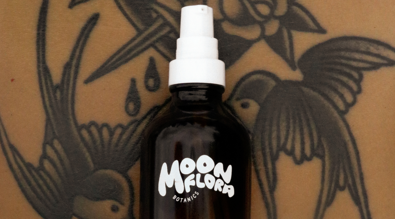 upclose shot of tattooed stomach with a bottle of body oil for a blog about the tattoo healing process