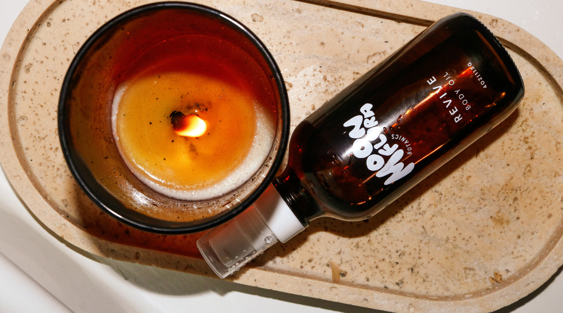 moonflora revive body oil next to a burning candle for a blog about new year 2026 rituals