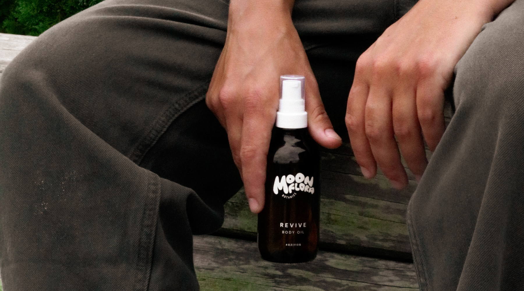 person holding bottle of moonflora botanics revive body oil for a blog about spring skincare tips 