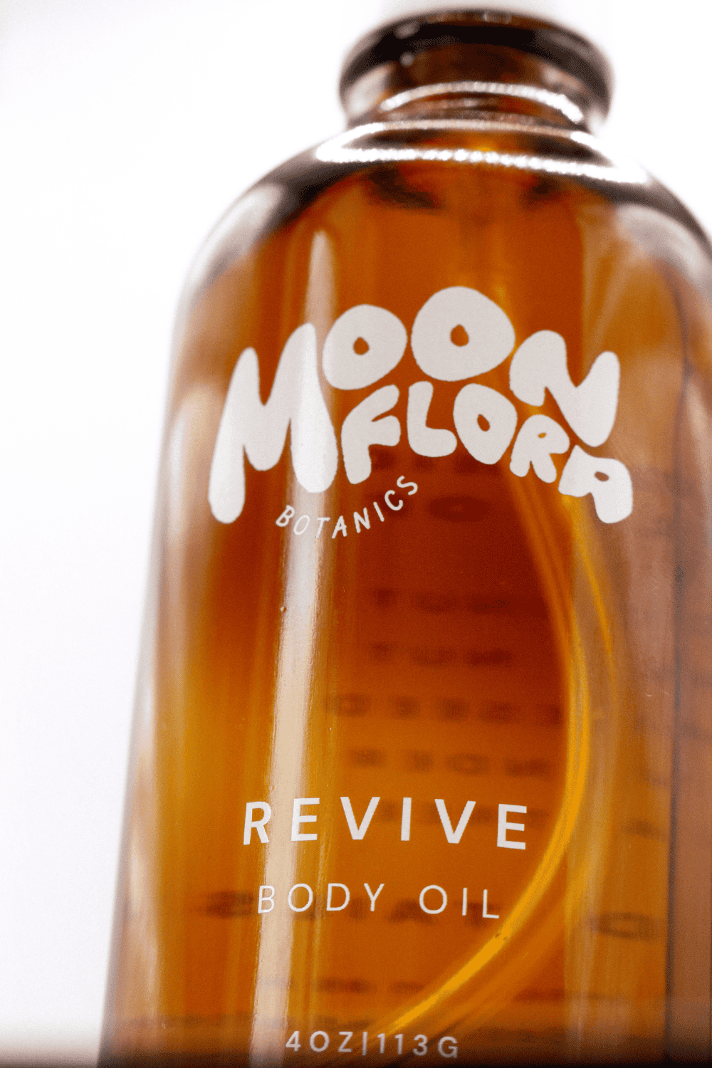 Bottle of Moonflora Botanics Revive organic Body Oil with a blurred background